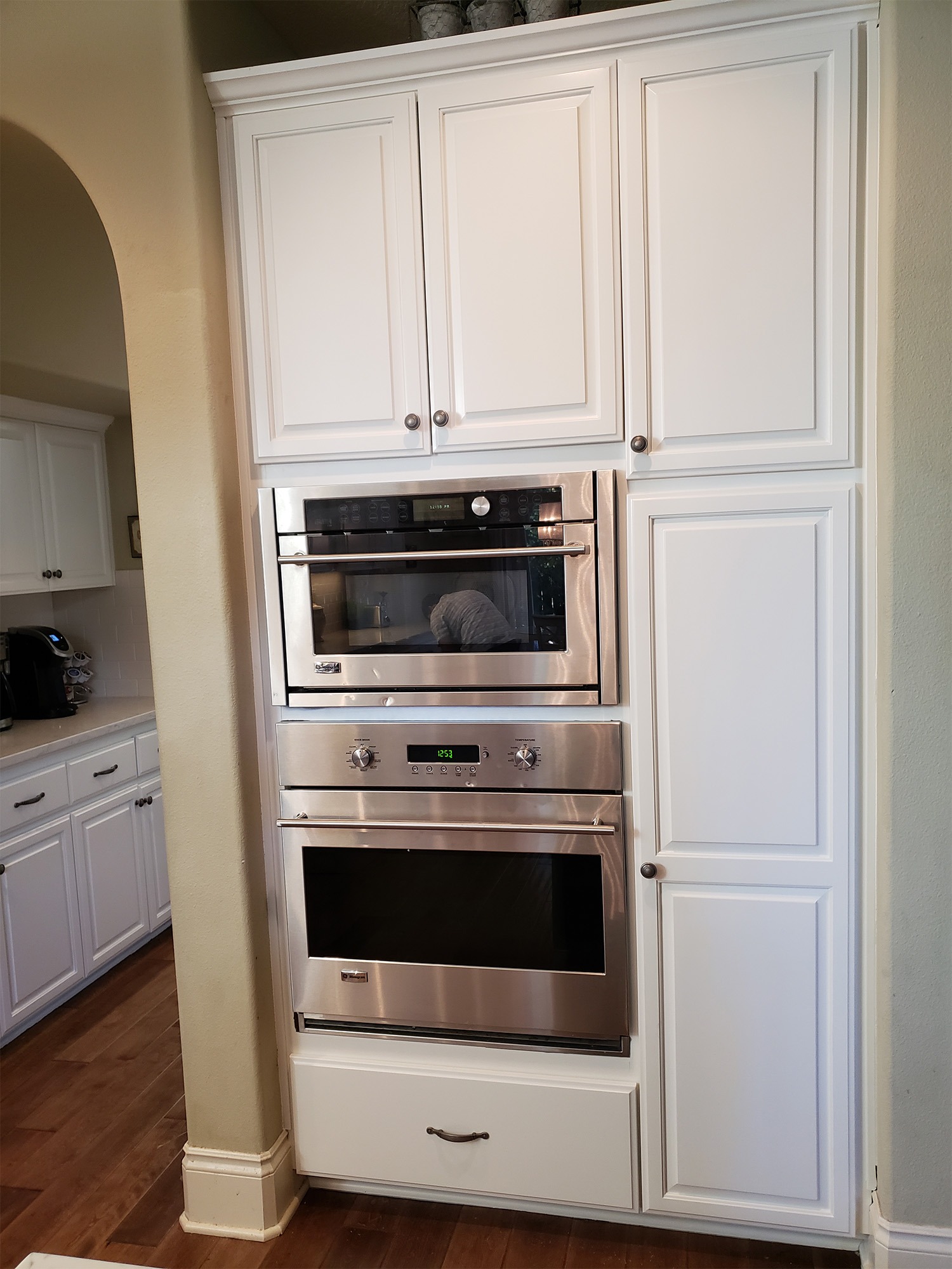 Modern kitchen featuring built-in stainless steel oven and microwave units, with white cabinetry above and below for a sleek, organized look.